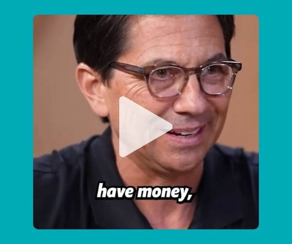 A man in glasses and a dark shirt is mid-conversation with a subtitle that reads “have money,” overlaid on the image, with a large play button in the center, indicating it’s a video clip. The background is turquoise.