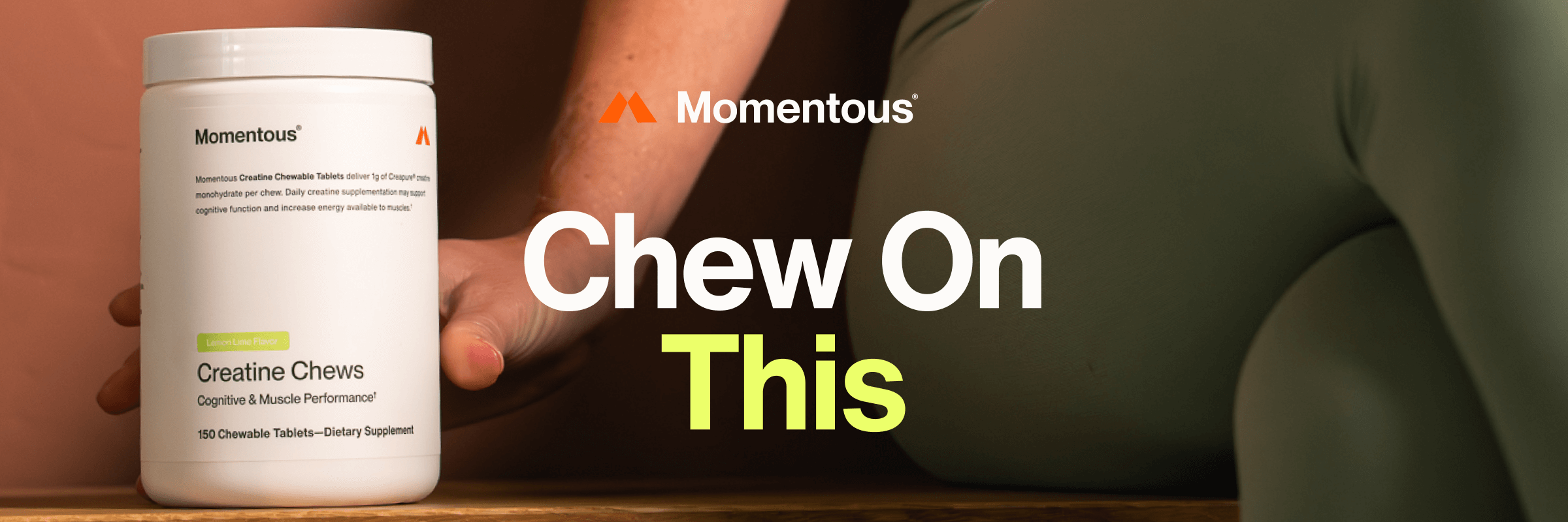  A close-up of a white tub of Momentous Creatine Chews in lemon-lime flavor held by a person in workout clothes. Bold text next to it reads “Chew On This” against a warm-toned background.