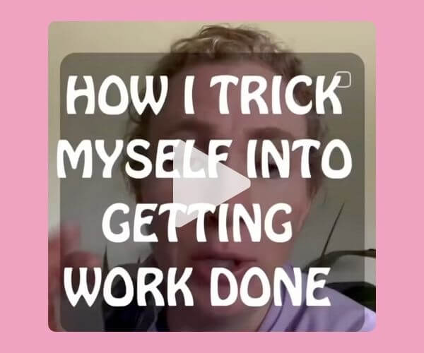 A video still shows a person with text overlay that reads, “HOW I TRICK MYSELF INTO GETTING WORK DONE.” The background is slightly blurred, focusing on the bold white text with a play button in the center.