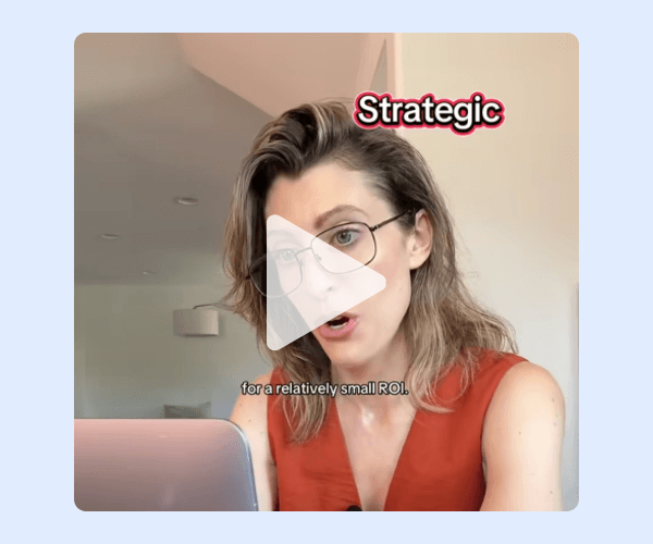 A woman with shoulder-length hair and glasses sits at a desk, speaking while looking at her laptop. The video overlay includes the word “Strategic” above her head and faint captions at the bottom.