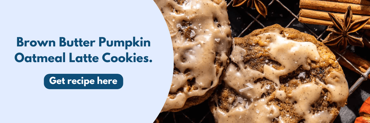 Close-up of warm, golden-brown pumpkin oatmeal cookies drizzled with a glossy brown-butter glaze, surrounded by cozy fall spices like cinnamon sticks and star anise.