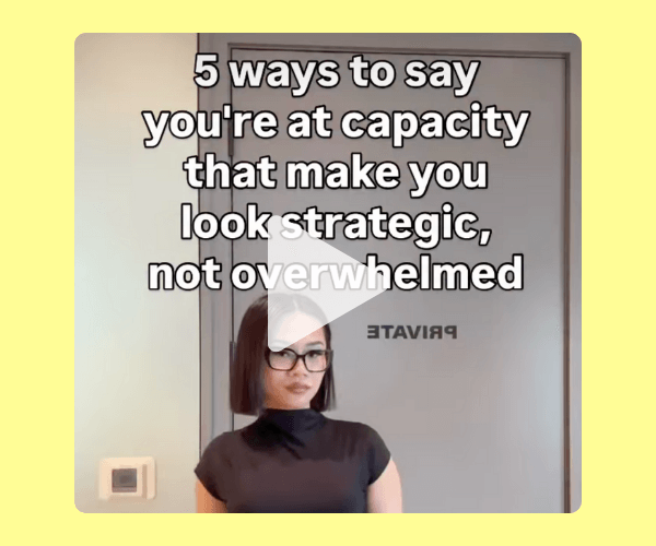 A video thumbnail shows a woman with a short bob haircut and glasses standing in front of a glass office door labeled “PRIVATE,” with bold white overlay text that reads, “5 ways to say you’re at capacity that make you look strategic, not overwhelmed.” The scene is framed by a solid pale yellow background border, contrasting with the neutral gray office setting behind her.
