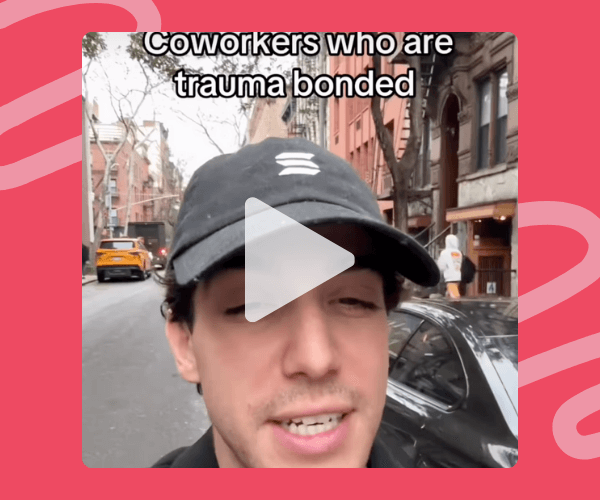 Close-up of a man wearing a black cap standing on a city street, with buildings and parked cars behind him. On-screen text reads, “Coworkers who are trauma bonded,” with a video play icon over the center.