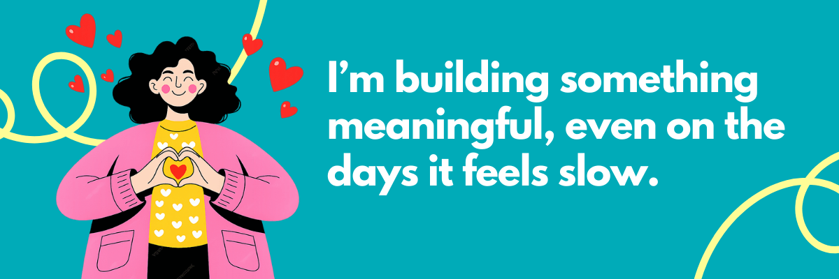 Illustrated graphic with a teal background and playful yellow swirls, featuring a smiling woman with curly black hair in a pink cardigan and yellow heart-print shirt forming a heart shape with her hands as red hearts float around her. Bold white text reads, “I’m building something meaningful, even on the days it feels slow.”