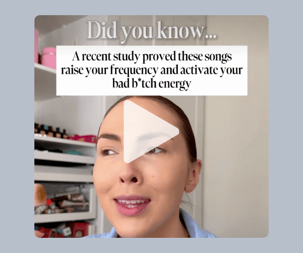 A woman speaks to camera in front of a makeup shelf, with a play button overlay on the video. On-screen text reads, “Did you know… A recent study proved these songs raise your frequency and activate your bad b*tch energy.”