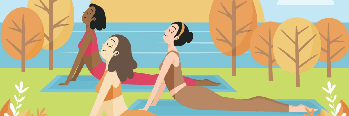 Three women practice yoga on mats in a calm outdoor setting with trees and water in the background. They are stretching in a relaxed pose, suggesting wellness and mindfulness.