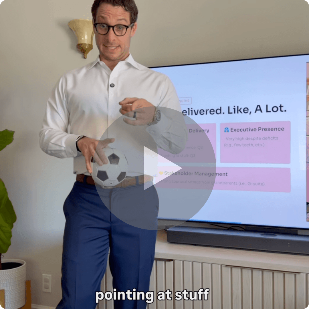 A man wearing glasses and business attire stands in front of a television displaying a presentation slide. He gestures toward the screen while holding a small soccer ball, with a large play button overlaid on the image.