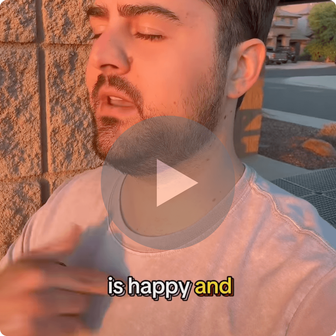 A video thumbnail shows a man speaking outdoors in warm evening light while leaning against a stone wall. The on-screen caption suggests he is discussing happiness or a positive mindset.