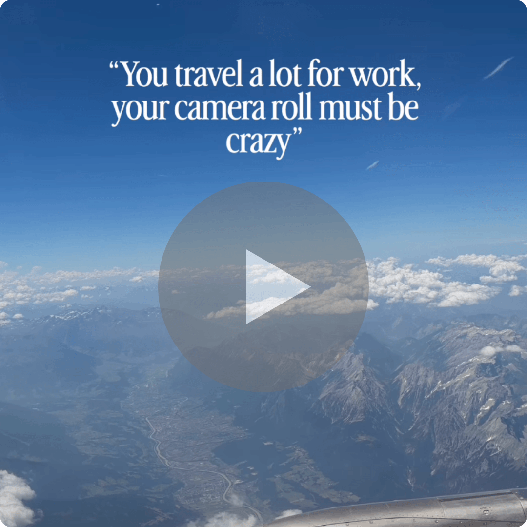 A video thumbnail shows an aerial view from an airplane window overlooking mountains and clouds under a blue sky. White text at the top reads, “You travel a lot for work, your camera roll must be crazy,” with a play button centered over the image.