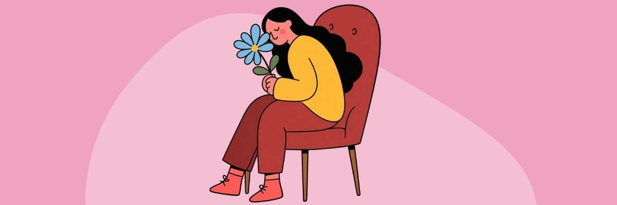 An illustrated woman in a yellow sweater and brown pants sits curled up in a brown armchair while holding a blue flower near her face. Pink and light-pink abstract shapes fill the background.