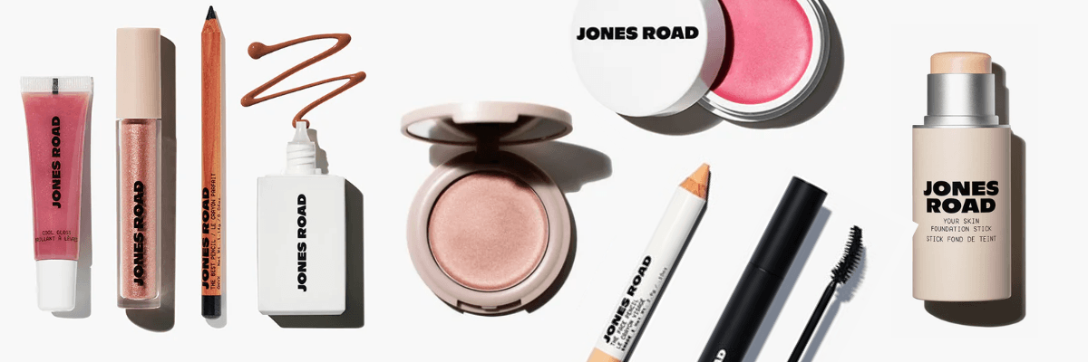 A collection of beauty and makeup products is neatly arranged against a clean background. The assortment includes lip products, foundation, mascara, and other everyday cosmetics.
