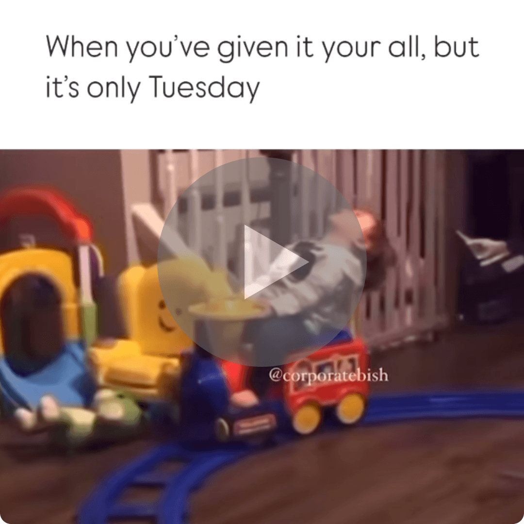 A video-style image shows a child sitting inside a small toy train while another child stands beside it. Text at the top reads, “When it’s only Tuesday but you’re already over it,” with a play button in the center.